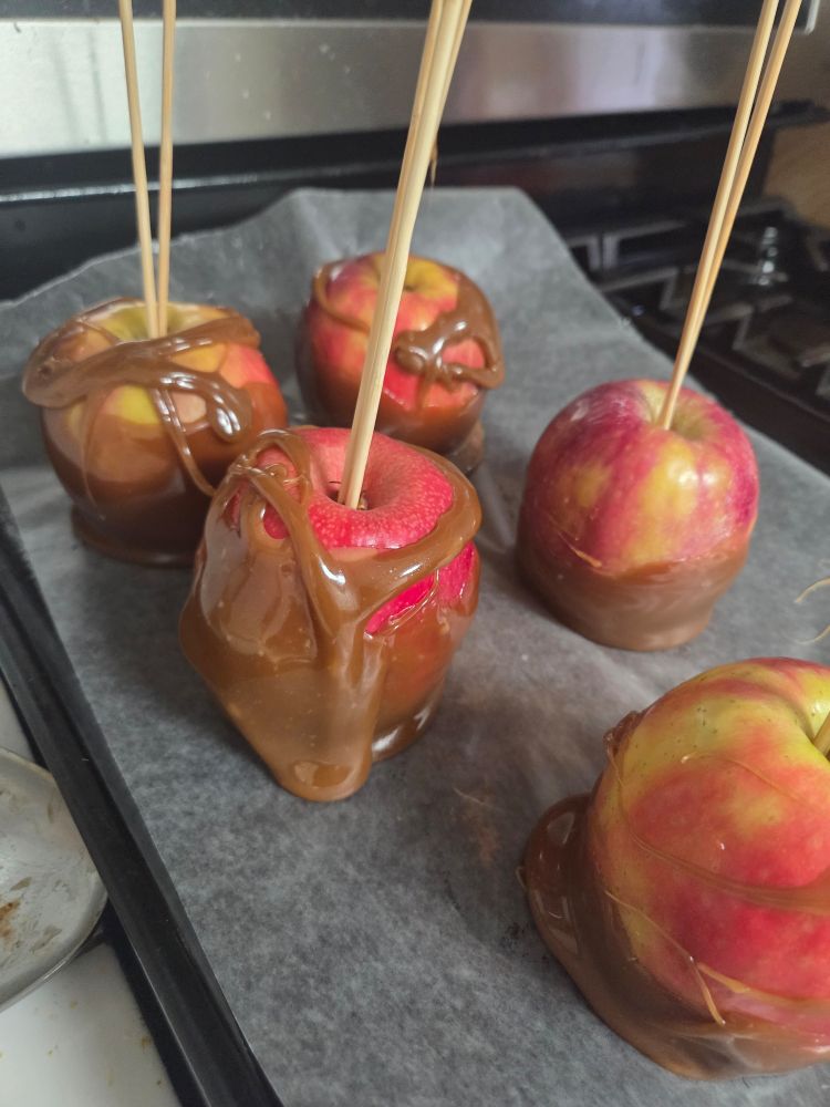 5 apples with sticks in them covered messily with caramel