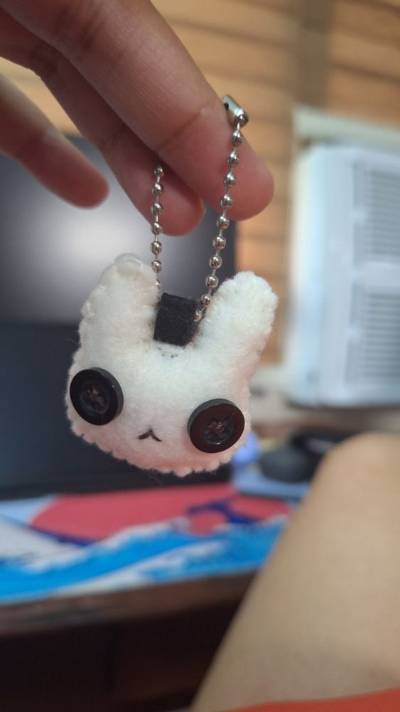 Felt keychain of a white bunny with black button eyes.