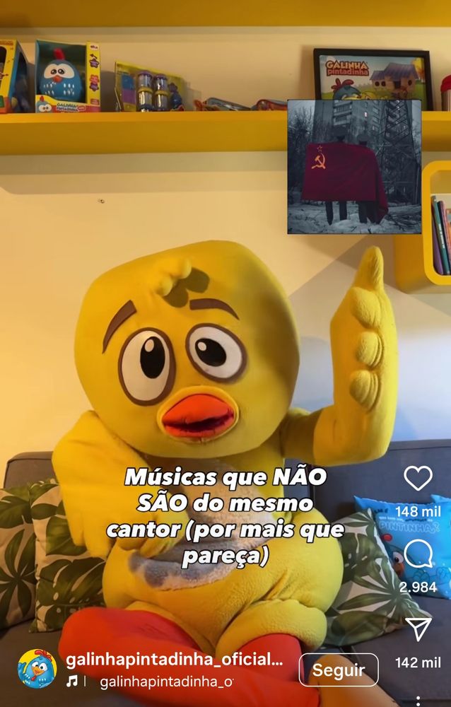 Galinha pintadinha apontado para um pequeno quadro em que duas pessoas estão com a bandeira da União soviética. 