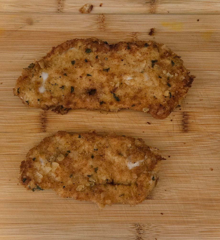 two chicken cutlets on a cutting board
