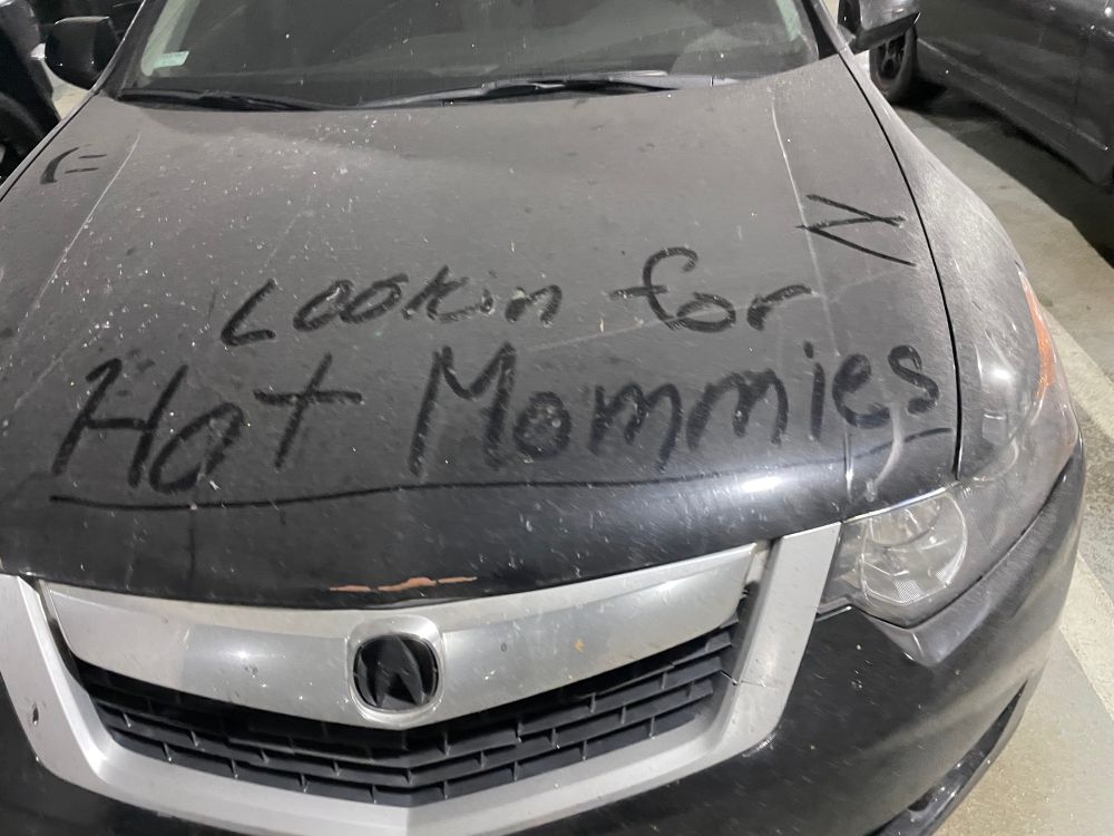 An extremely dusty car with the words “Lookin for Hot Mommies” written on the hood. I hope the car finds those hot mommies.