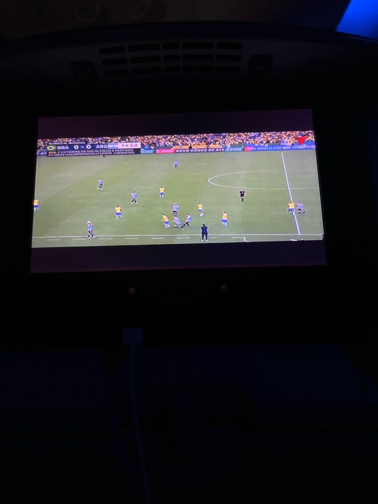 A picture of a soccer game on in flight screen, the cabin is dark.