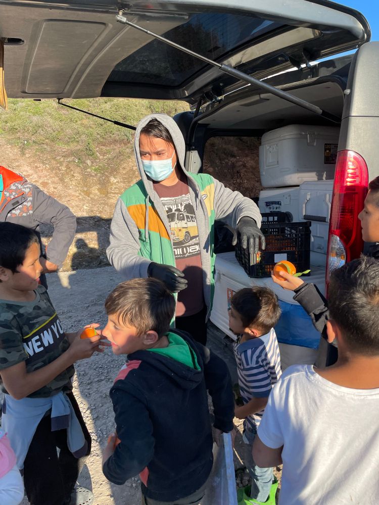 Habib im Camp auf Lesbos, von Kindern umringt, denen er Süßigkeiten verteilt 
2020