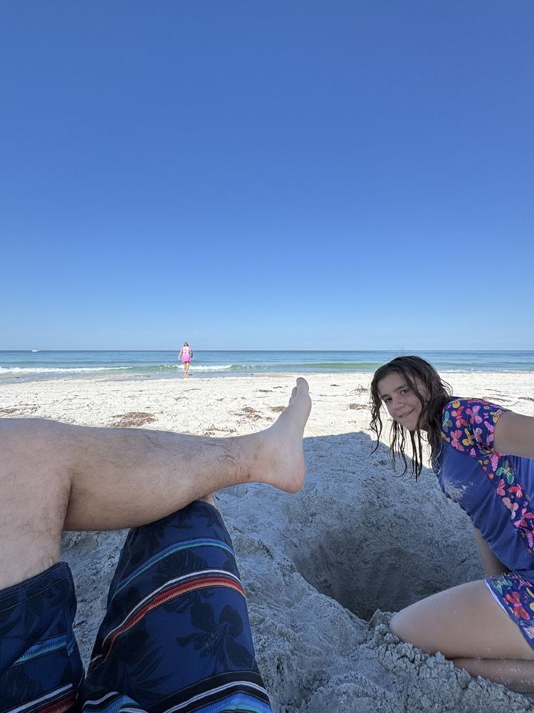 One of my kids digging a hole while the other plays in the surf at the beach this morning.