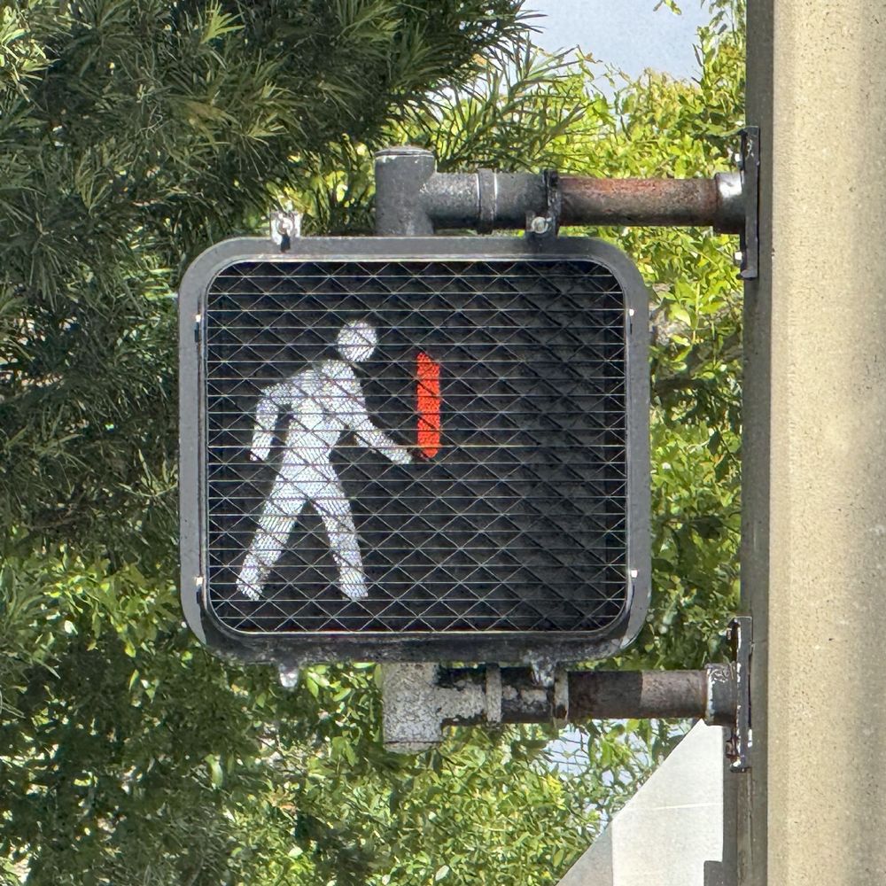 Photo of a crosswalk signal displaying a red bar in front of the walk signal that looks like a light saber.