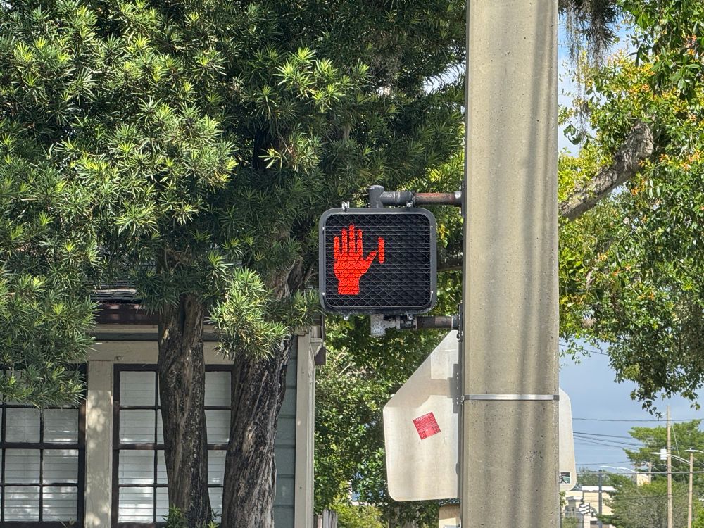 Photo of the crosswalk signal with the same red bar still present but next to the red, don’t walk hand.