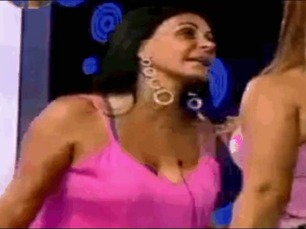 a woman wearing a pink tank top and earrings is standing next to another woman .