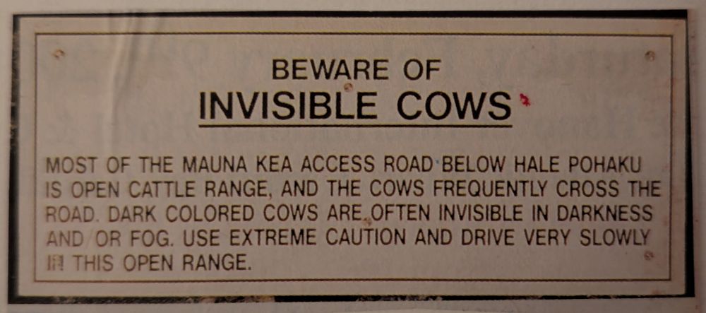 A sign saying 

"BEWARE OF
INVISIBLE COWS

MOST OF THE MAUNA KEA ACCESS ROAD BELOW HALE POHAKU IS OPEN CATTLE RANGE, AND THE COWS FREQUENTLY CROSS THE ROAD. DARK COLORED COWS ARE OFTEN INVISIBLE IN DARKNESS AND OR FOG. USE EXTREME CAUTION AND DRIVE VERY SLOWLY IN THIS OPEN RANGE."