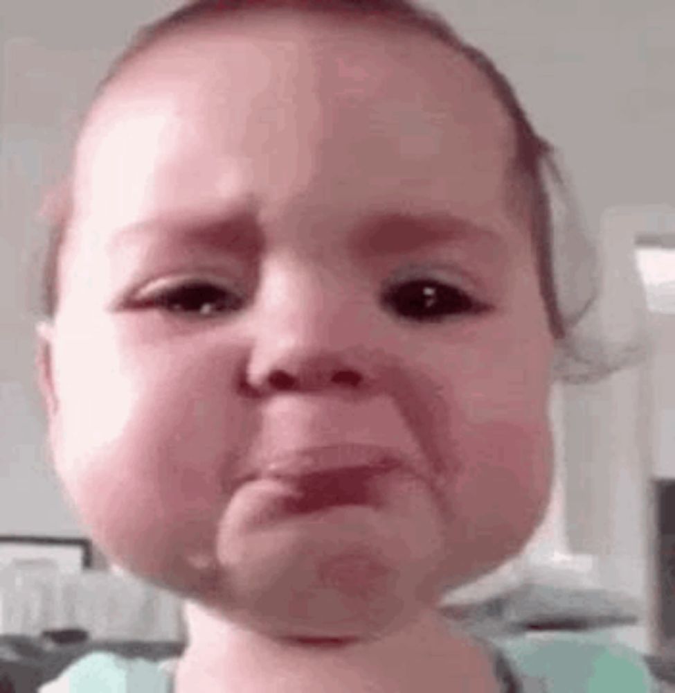 a baby is crying and making a funny face with tears running down his face .