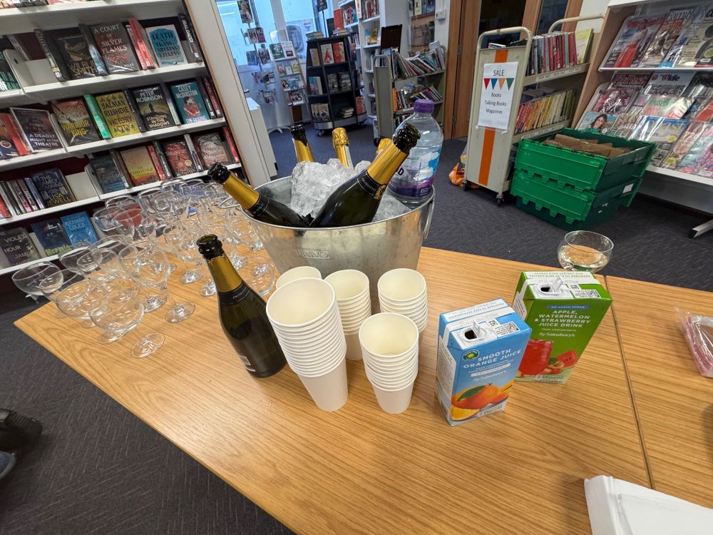 Wine glasses, bottles of prosecco in a tub of ice, cups and fruit juice cartons