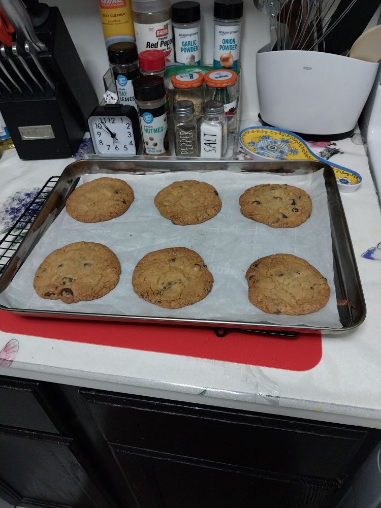 Fresh-baked chocolate chip cookies cooling on a kitchen counter.
