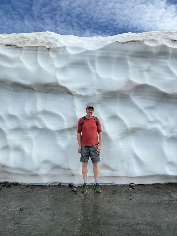 Daniel, who is 6’7”, in front of a wall of snow probably 12 feet tall