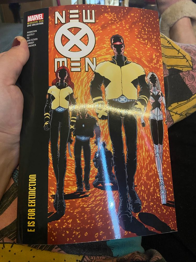 The cover of New X-Men Modern Epic Collection Volume 1: E Is For Extinction, reproducing the cover of New X-Men #114

Cyclops, Jean Grey, Emma Frost, Wolverine and Professor X approach the reader, their faces in shadow. The background is a swirl of sparks in shades of orange and yellow.