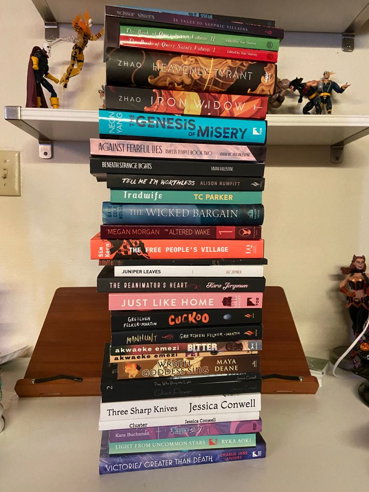 A slightly precarious stack of twenty-nine books by various trans, non-binary and otherwise gender non-conforming authors. The books are a mix of paperbacks and hardcovers of various sizes, and pretty much all fall under the sci-fi/fantasy/horror umbrella.