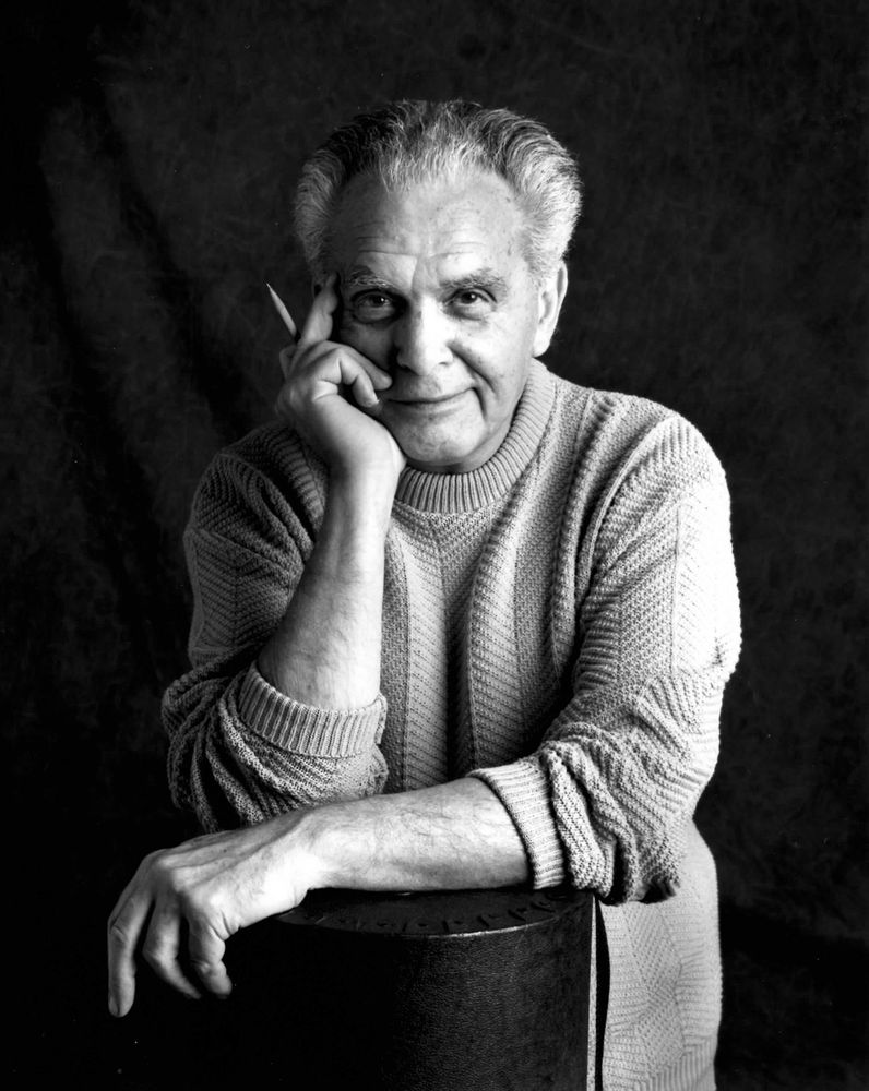 Black and white portrait of Jack Kirby holding a pencil, taken by Suzy Skaar in 1992, licensed under a Creative Commons Attribution-ShareAlike 3.0 Unported License.