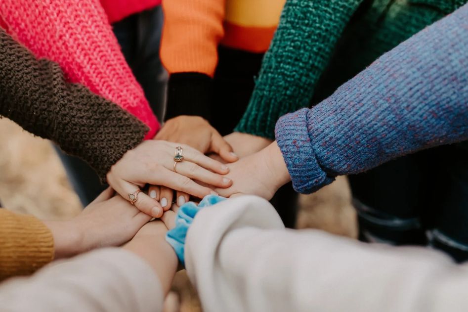 Image shows group of people putting hands together