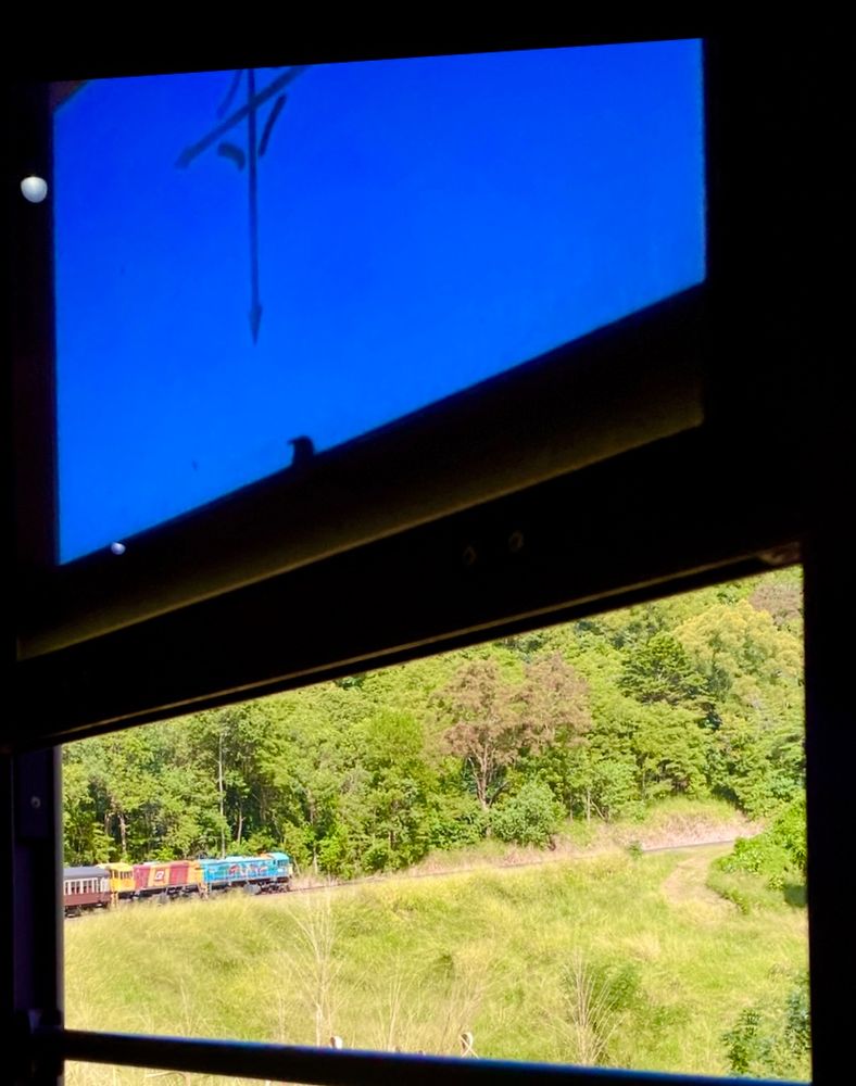 Looking through a train window at the Australian bush. The train’s engine is visible, as the train traverses a tight right hand bend in the railway track.