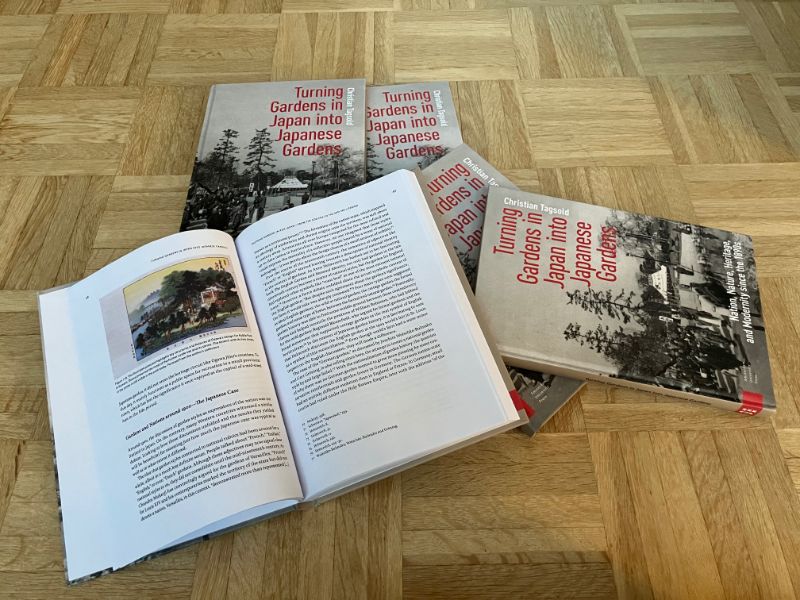 Five books are lying on the floor. One is open and shows an image on the upper left page.