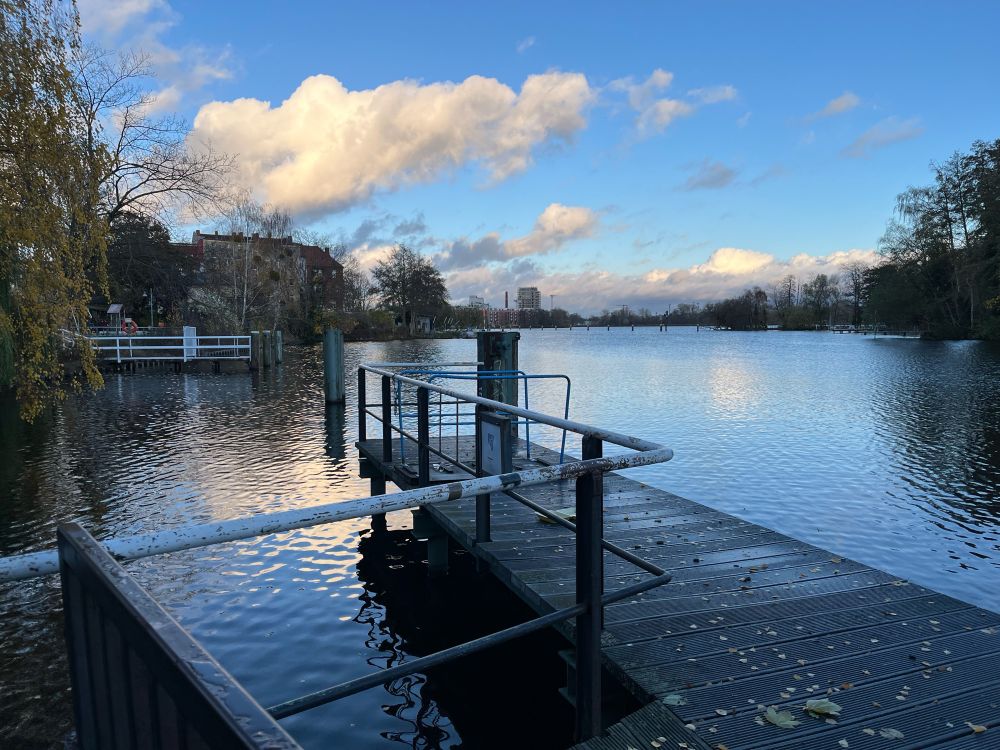 Die Havel in Spandau am Wröhmännerpark. Im Vordergrund ein Bootssteg, im Hintergrund blauer Himmel mit ein paar Wolken. 