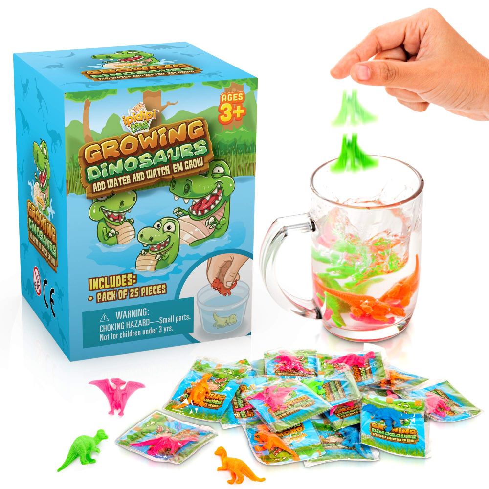 A box of GROWING DINOSAURS toys next to several packs and a glass of water with the toys being dropped inside to grow.