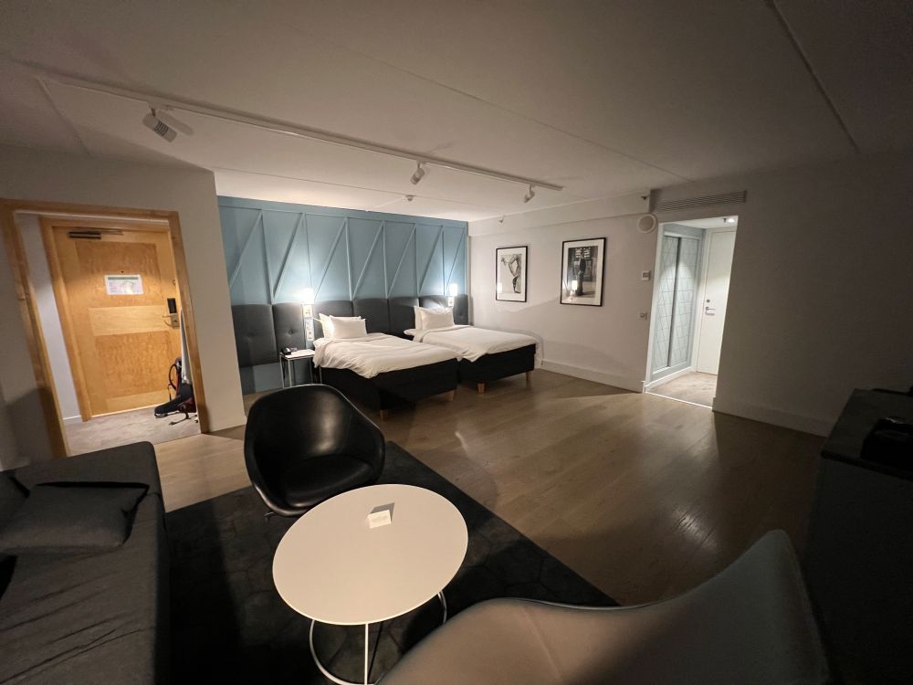 Del av junior suiten. Viser bord, stoler og to senger. Stort rom.