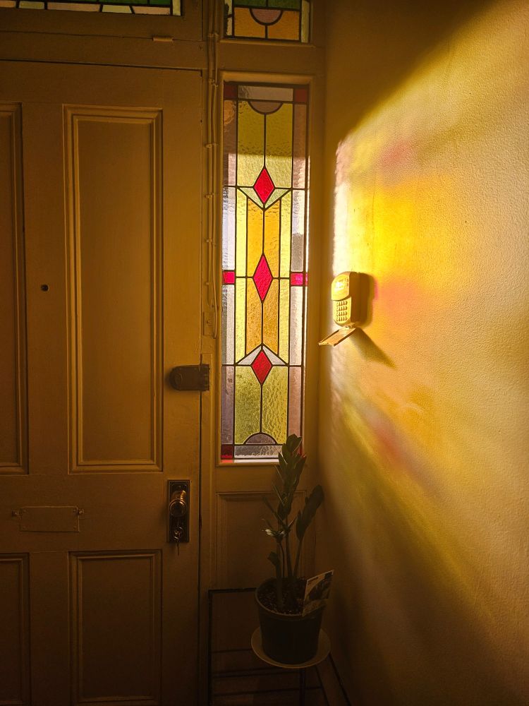 Sun shining through a stained glass window next to a door
