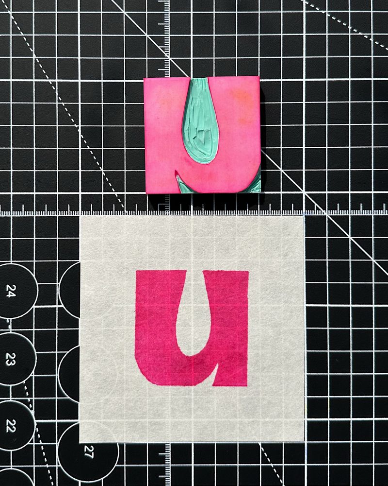 Letter U linocut and stamped on paper in magenta 