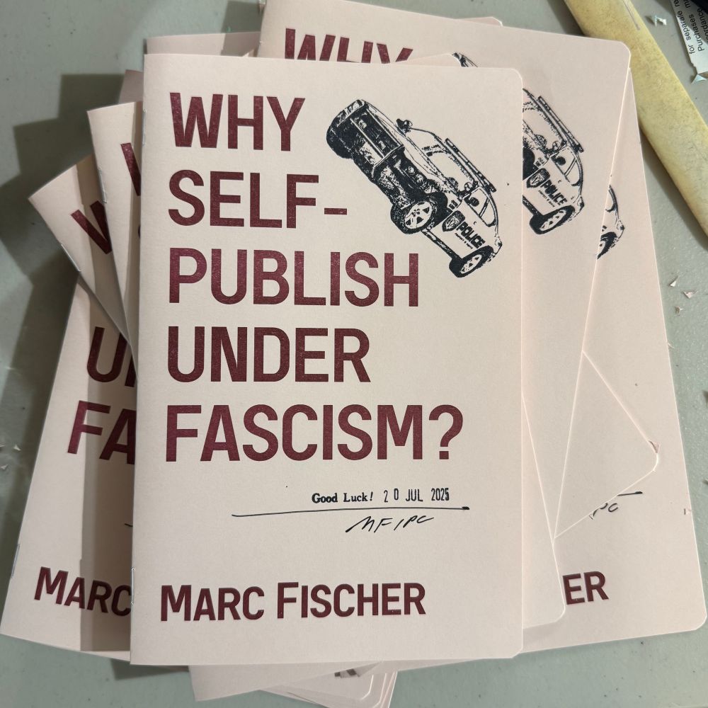 A stack of the booklet Why Self-Publish Under Fascism? by Marc Fischer with burgundy printing and black ink rubber stamping on reddish beige paper.