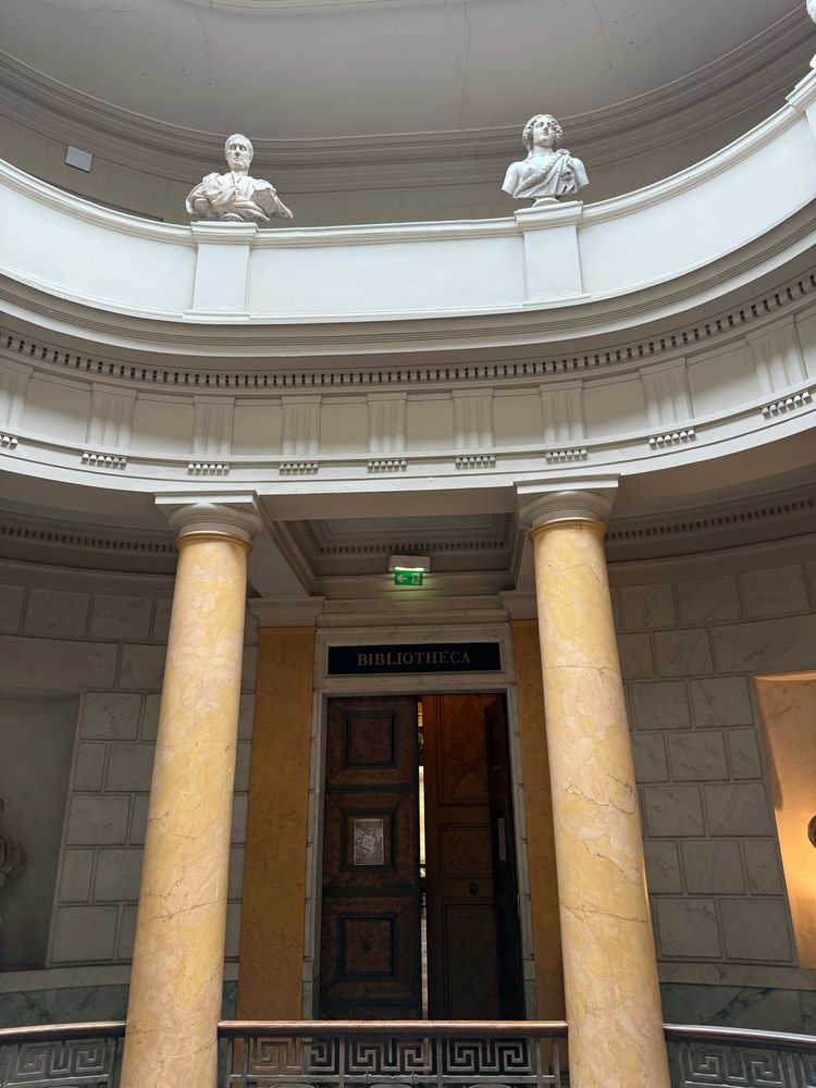 Ein Foto zeigt den inneren Eingang zur Bibliothek an einem Treppenaufgang in einem Kuppelbau. 