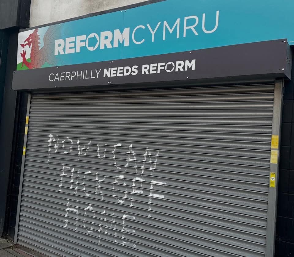 The reform offices in Caerphilly with @m”now you can fuck off home” graffitied on the shutters in white print 