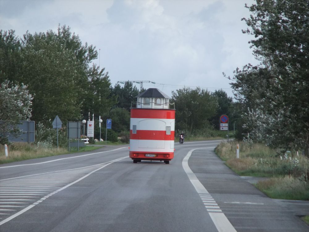 Anhänger mit einem kleinen rot-weißen Leuchtturm drauf auf der Straße