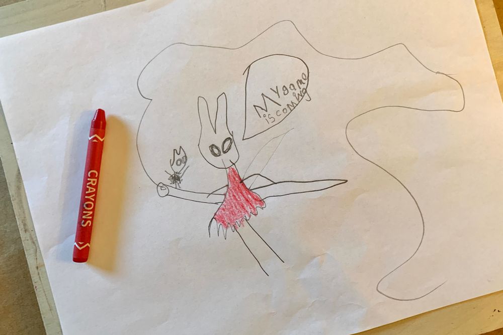Photo of a child’s drawing of a bug-like creature in a red cloak wielding a giant threaded needle with a speech bubble that says “My game is coming”. A smaller bug sits on the end of the needle