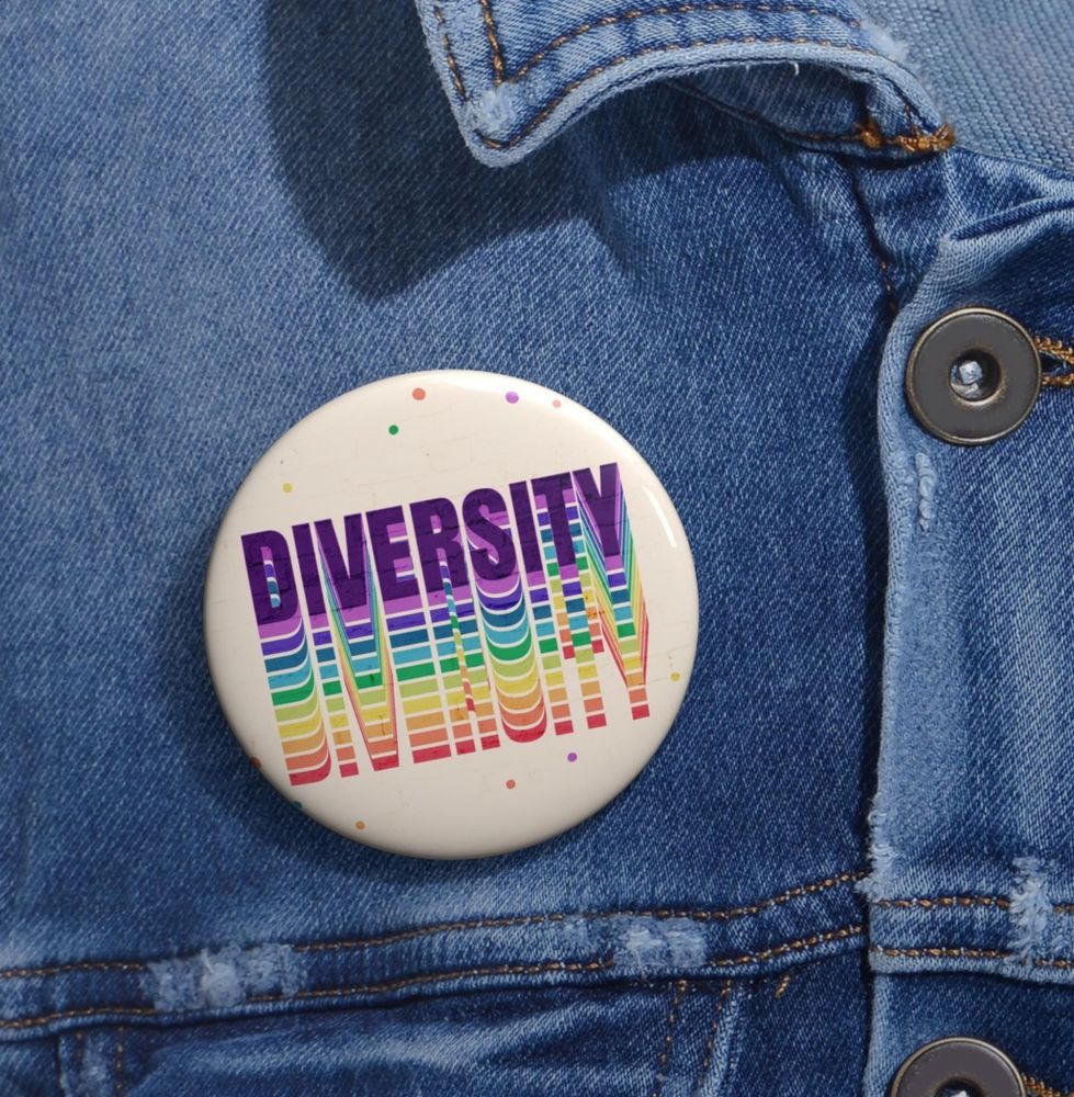Button pin that says DIVERSITY in rainbow of colors with a off white background