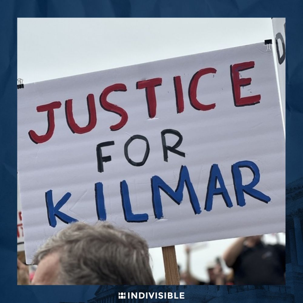 A person holding a sign that reads "JUSTICE FOR KILMAR" at a demonstration, with the logo "INDIVISIBLE" at the bottom.