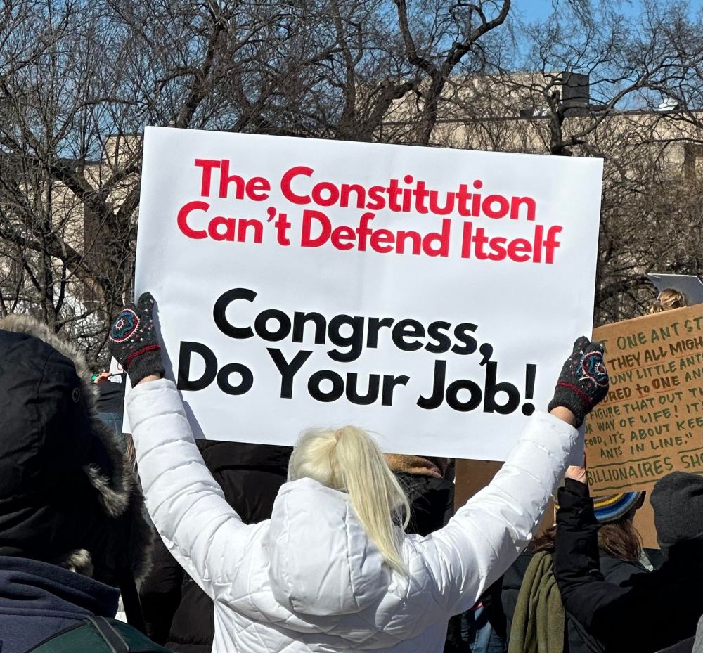 A sign is held up at a protest that reads “The Constitution Can’t Defend Itself

Congress, Do Your Job!”