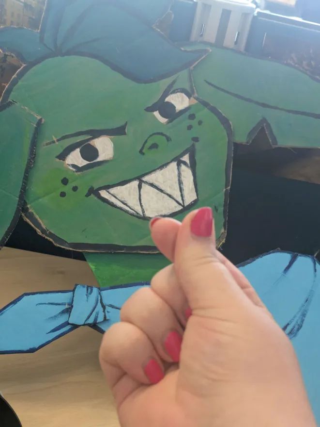 A member of the development team for Gobblin' holding out a heart sign in front of a cardboard cutout of our main character for the game Gobblin'
