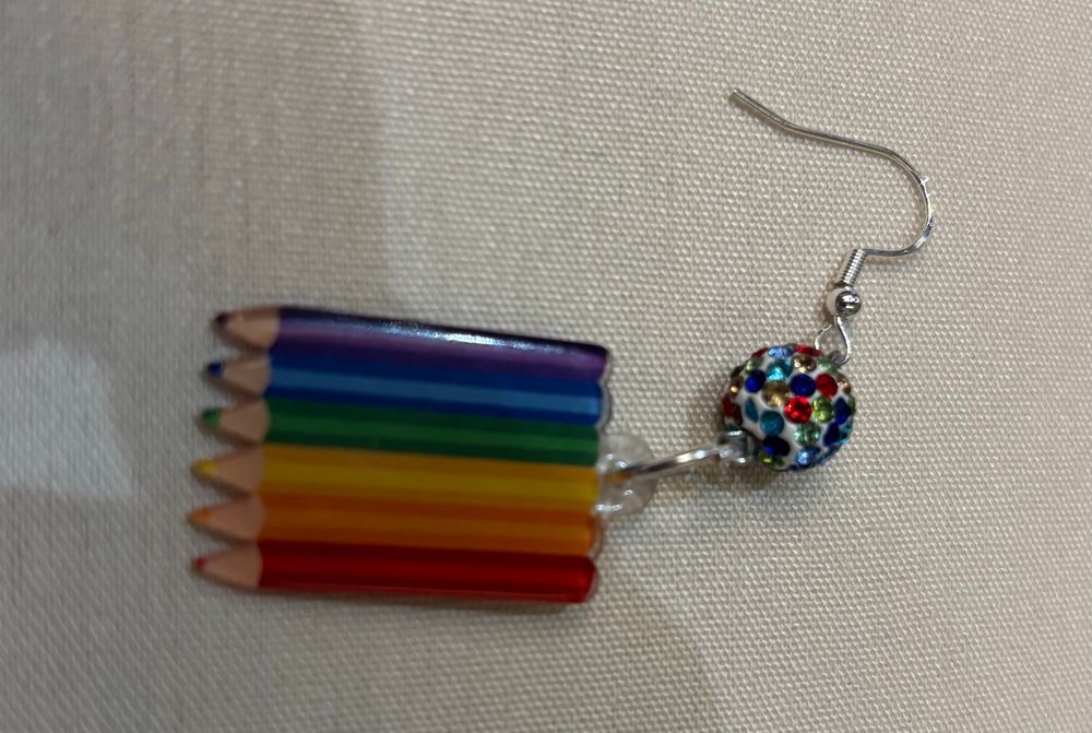 photo of a single earring: rainbow color pencils and a disco ball