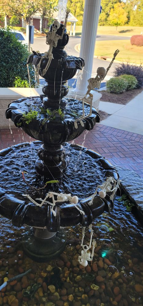 5 small skeletons doing shenanigans on the edge of the 3teirs of a giant fountain