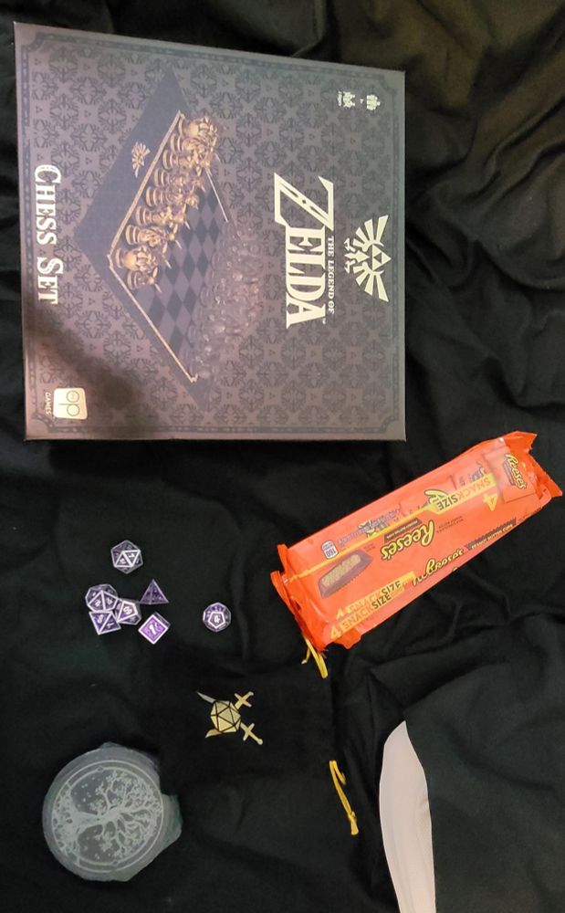 The birthday presents my family gave me today! A Legend of Zelda chess set, a set of metal dice and a dice bag, some slate coasters, and thee 4-packs of Reese's Peanut Butter Cups!