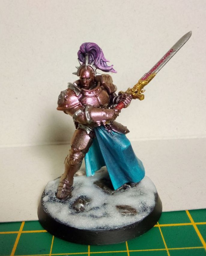Valantin Harvestblade, Hero of the Gladitorium, standing tall and proud on a snowy base, ready to smite the enemies of Sigmar! 
Resplendent in his shimmering, orange to purple armor, with a teal skirt and pink tail on his helmet he is ready to reap lives instead of corn with his huge Zweihänder, market with Flourescent Magenta runes.