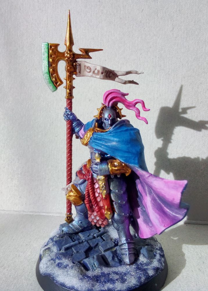 Tenya Thrice-Trusted, who somehow is called Thrice-Cursed in German (Dreifluch), standing proud.
I think this one might be a bit too colorful, but it was still fun to paint him up. Tried something new with the halberd blade, from TAP Glittering Green up to Shining Silver to give it a more magical look. 
Tried having some fun with the base as well, under the snow is Royal Purple to Alien Purple from Vallejo as dry brush, with the ruins being a few layers of Tan Green and Dead White Vallejo airbrush paints painted on with a normal brush. 
Just playing around with random colors to see what will happen.