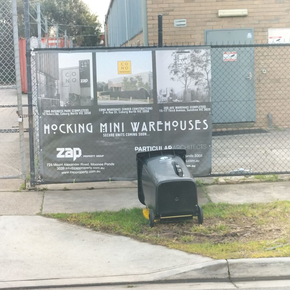 Big wire mess fence with real estate sign attached - the sign says 'Hocking mini warehouses' in a type font of Charlie Rennie Mackintosh 