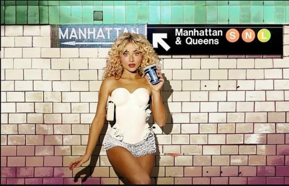 sabrina carpenter in front of a wall in a subway station. to the right of her is a sign with a left arrow that says “manhattan & queens SNL” 