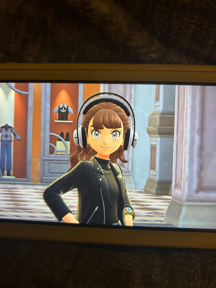 me in pokemon legends: z-a wearing a black leather jacket and white over the ear headphones