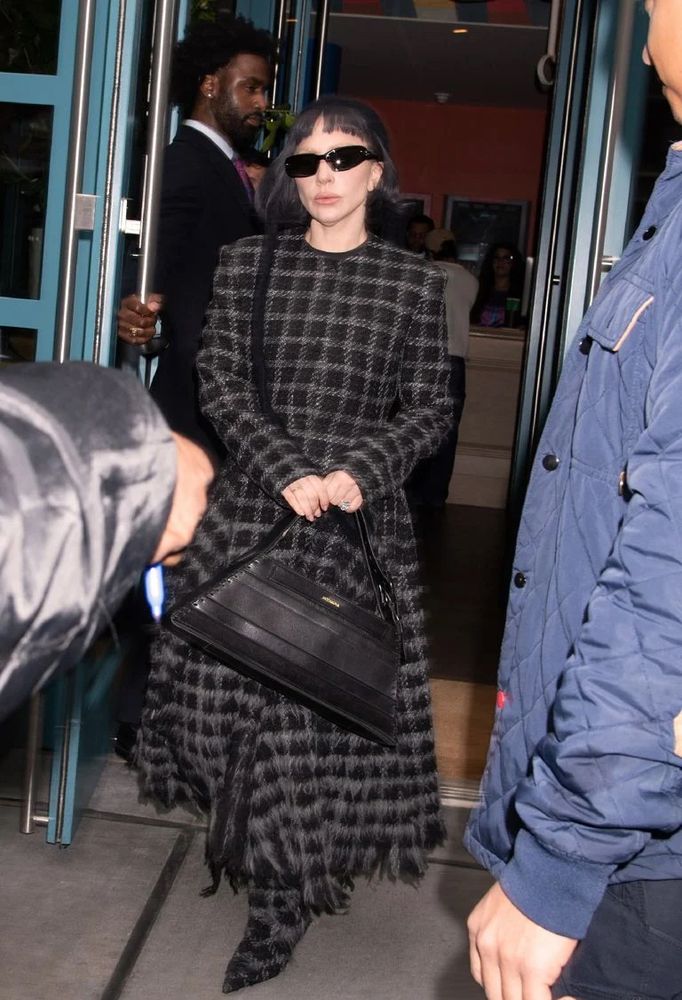 lady gaga wearing a grungey dark plaid dress and black sunglasses. 
