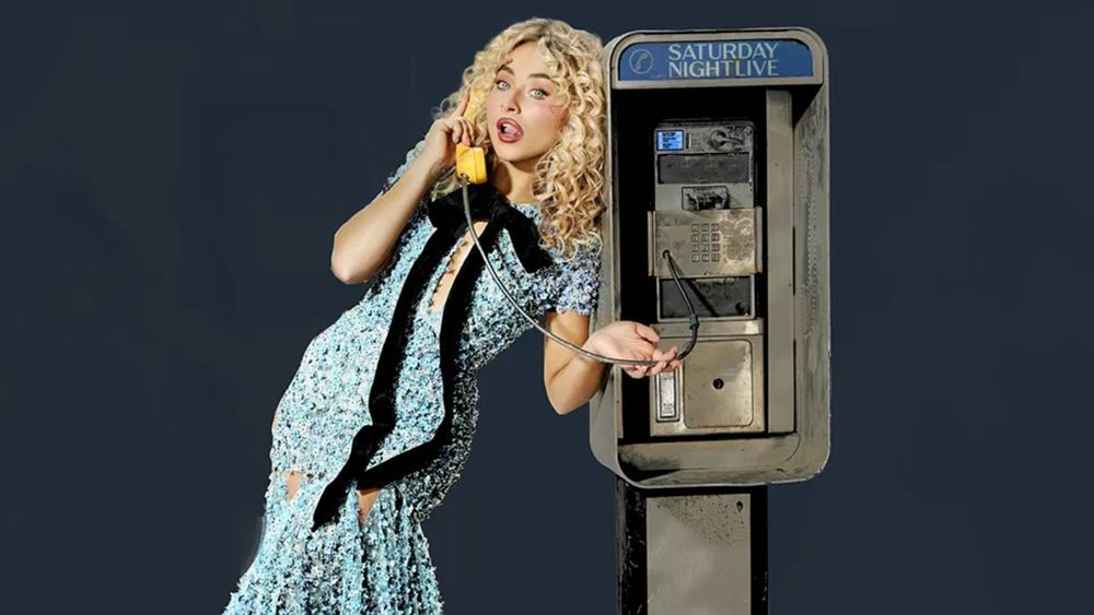 sabrina carpenter for snl, wearing a blue dress and standing next to a payphone, holding the phone up to her ear. 