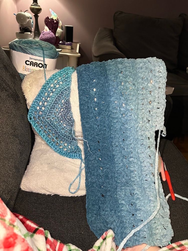on the left: the humble (dinky) beginnings of a crocheted shawl, using variegated yarn in shades of blue and blueish-purple. the cotton/acrylic blend is slightly shiny in the lighting. 

on the right: the first ~1/4 of a lap blanket, also crochet. the yarn has a gradient which starts out dark blue, then gradually becomes near-white. the yarn is fuzzy and chunky with no shine in the lighting. 