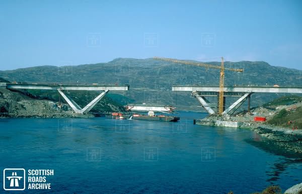 The central suspended span being lifted by cranes into place at Kylesku Bridge in Sutherland Scotland on 8 August 1984. It is a reinforced concrete cantilever bridge built on a curve, and on 45 degree angled supports