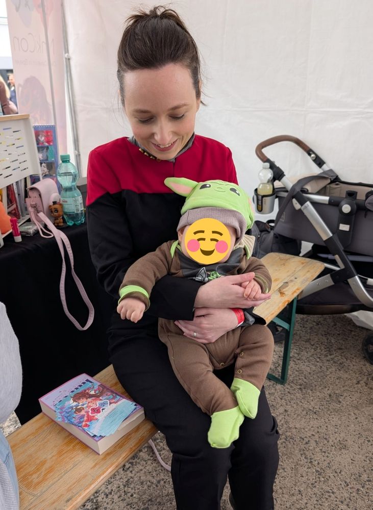 Me wearing a Star Trek Voyager uniform with my 5 month old nephew wearing a Grogu suit ob my lap