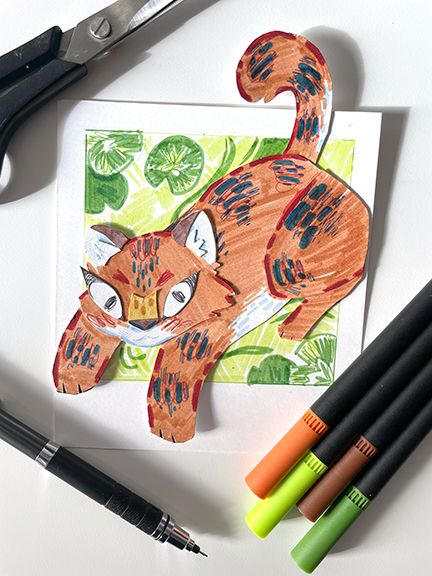 An illustrated papercut tiger with blue and red stripes, on a green background with lily pads, made to look like a polaroid. Photographed from above on a white surface with markers, a pencil, and scissors.